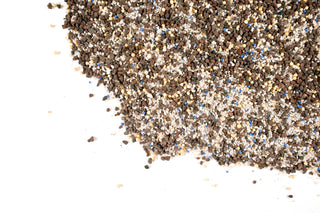 A pile of small granular substrate or soil mix containing dark brown, beige, white, and blue pieces, photographed on a clean white background.
